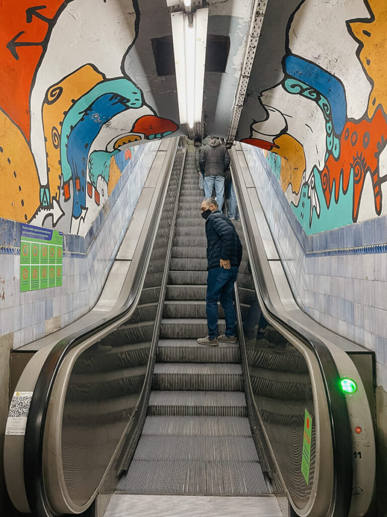 An escalator under an archway painted in a colorful mural in Buenos Aires