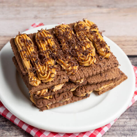 A chocotorta presented on a white plate placed on a white and red checkered napkin