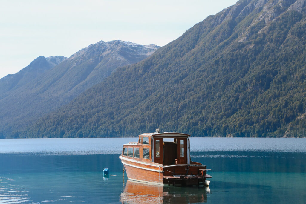 A wooden boat floats oared in a Correntoso Lake Villa La Angostura