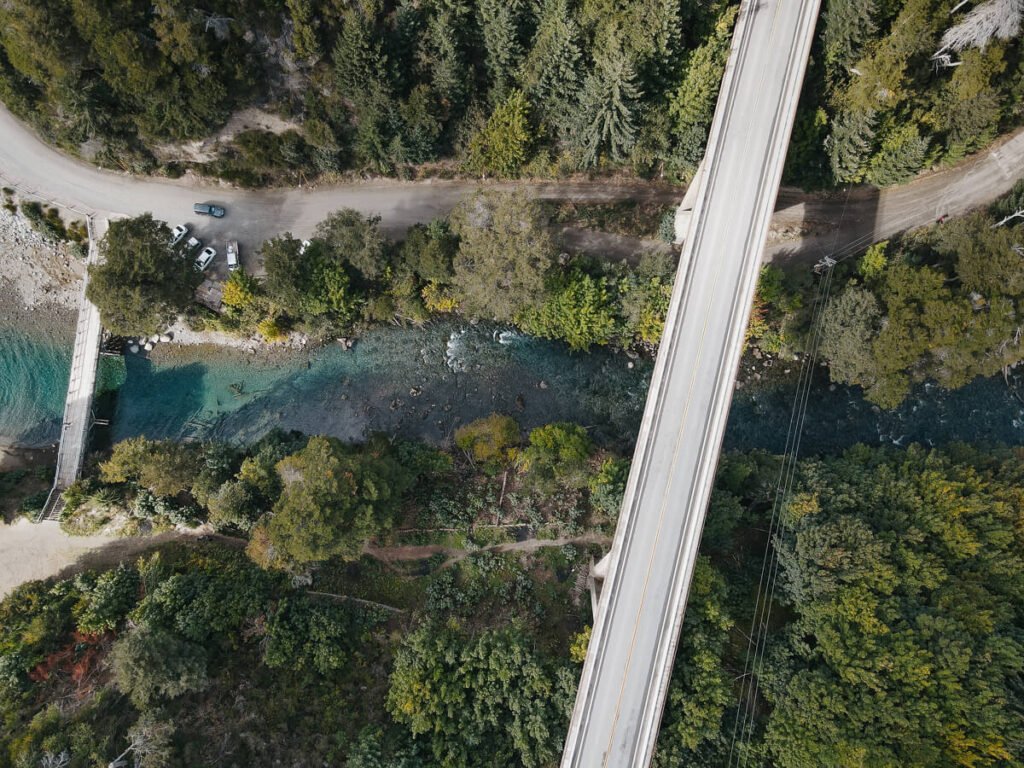 An aerial shot of a turquoise river with two bridges crossing it