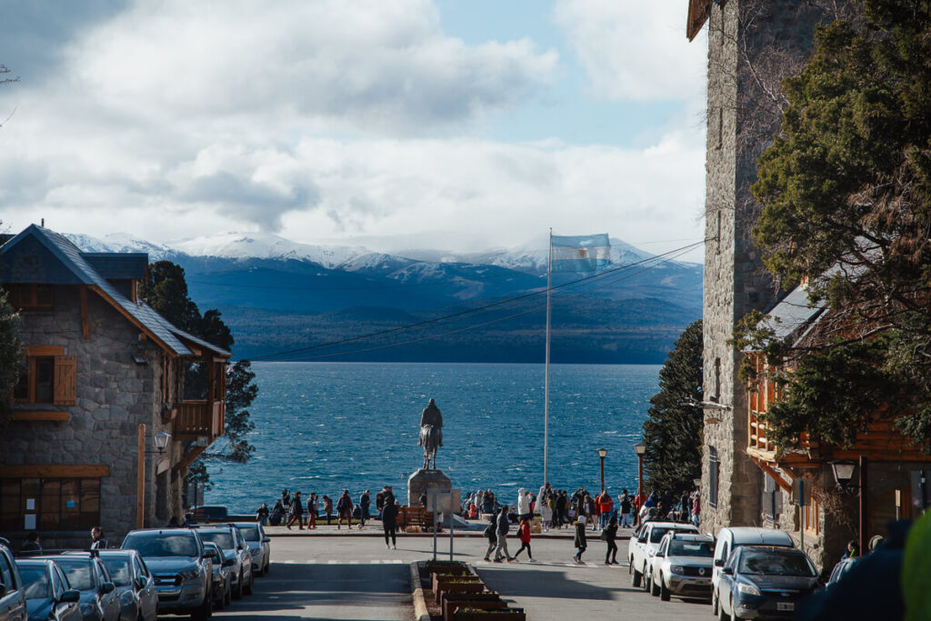 View of a boulevard leading down to Lago Nahuel Huapi lake with stone buildings flanking a large square