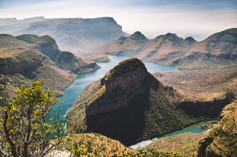 A turquoise river weaves through the green Blyde River Canyon rock formations