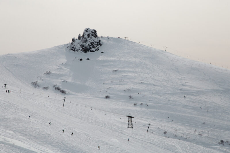 Skiers seem tiny as they go down a huge white mountain under ski lifts on an Argentina ski resort